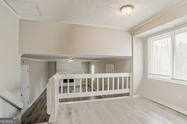 interior space featuring ornamental molding, a textured ceiling, baseboards, and wood finished floors