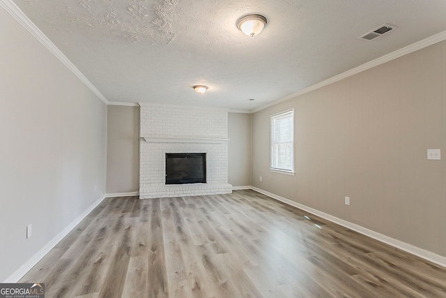 unfurnished living room featuring visible vents, a brick fireplace, wood finished floors, and ornamental molding