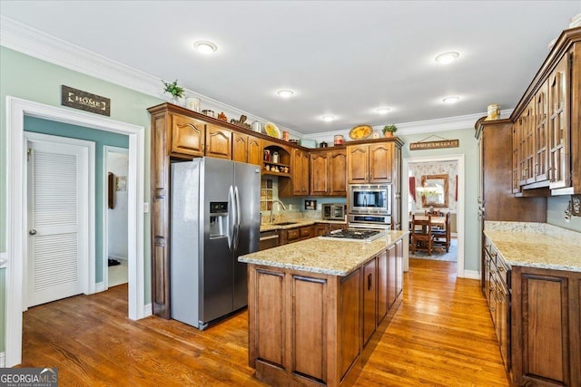 kitchen with light stone countertops, a kitchen island, open shelves, a sink, and appliances with stainless steel finishes