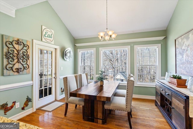 dining room with a chandelier, baseboards, wood finished floors, and vaulted ceiling