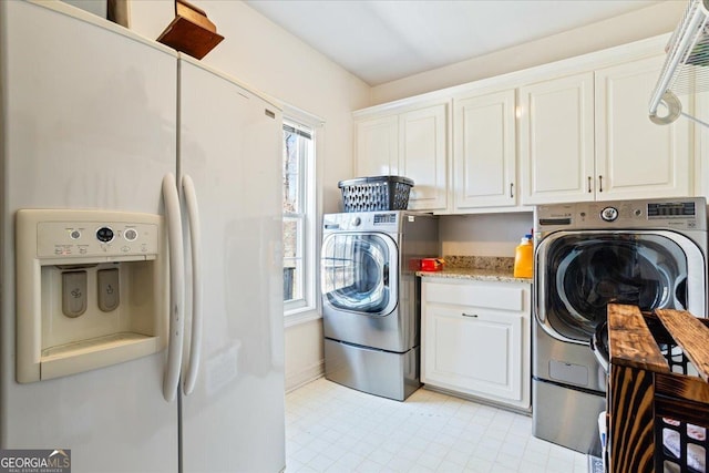 laundry room featuring cabinet space, light floors, and washing machine and clothes dryer