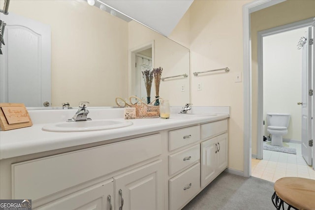 bathroom featuring a sink, baseboards, toilet, and double vanity