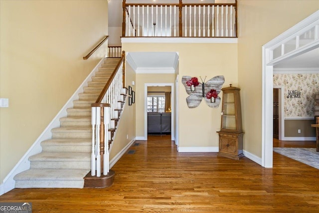 foyer entrance with crown molding, baseboards, stairs, a high ceiling, and wood finished floors