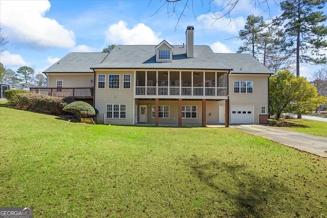 back of house with a yard, driveway, a sunroom, and a chimney