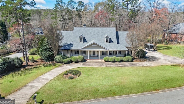 new england style home with a front lawn, covered porch, and driveway