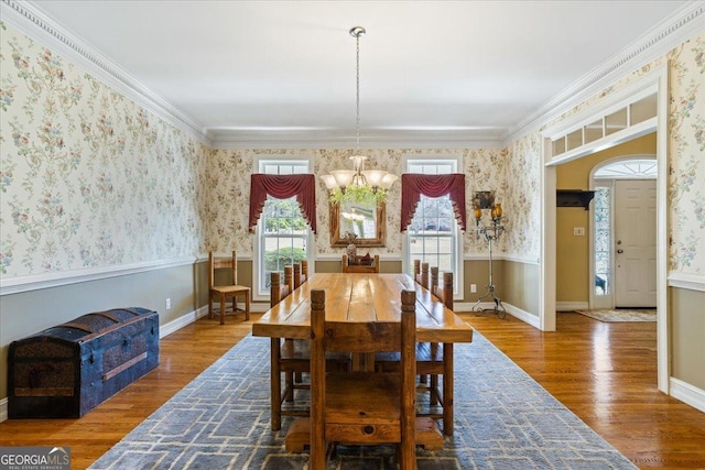 dining room featuring ornamental molding, wood finished floors, wainscoting, and wallpapered walls