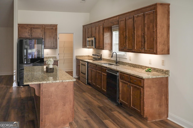 kitchen with a kitchen island, dark wood-style flooring, a sink, black appliances, and a kitchen bar