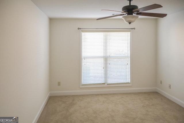 spare room featuring a ceiling fan, a healthy amount of sunlight, and light colored carpet