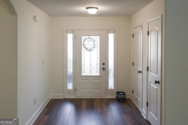 entryway with dark wood-style floors, arched walkways, and baseboards