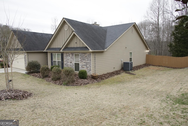 view of side of property featuring cooling unit, fence, stone siding, a lawn, and board and batten siding