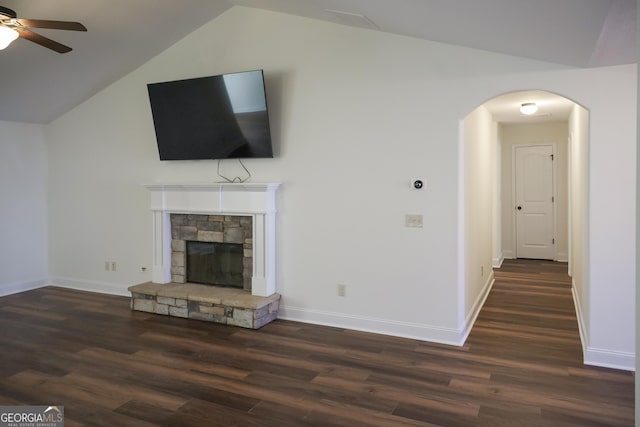 unfurnished living room featuring a ceiling fan, wood finished floors, a fireplace, arched walkways, and vaulted ceiling