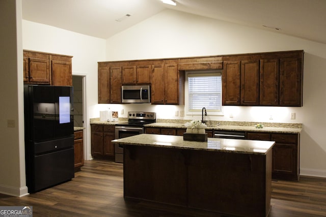 kitchen with light stone counters, dark wood-style floors, a kitchen island, a sink, and stainless steel appliances