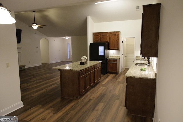 kitchen featuring a ceiling fan, visible vents, a kitchen island, arched walkways, and a sink