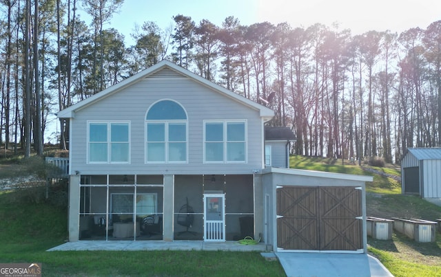 back of house with an attached garage and a sunroom