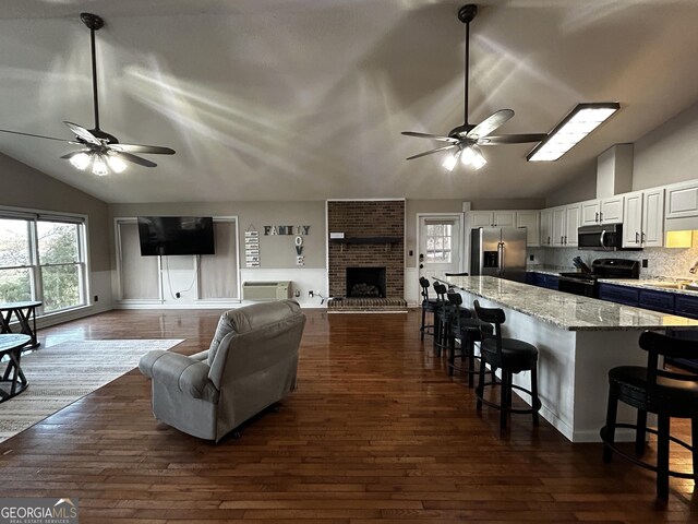 1550 Shady Oaks Ln, Greensboro, GA 30642 - living room featuring dark wood-style flooring, ceiling fan, vaulted ceiling, and a healthy amount of sunlight