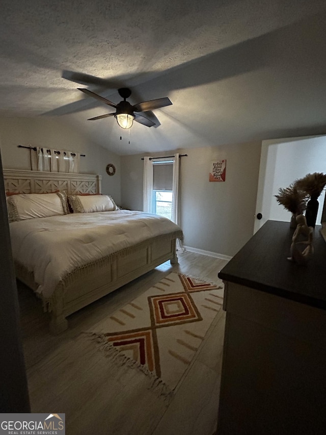 1550 Shady Oaks Ln, Greensboro, GA 30642 - bedroom featuring baseboards, a textured ceiling, a ceiling fan, light wood-style flooring, and vaulted ceiling