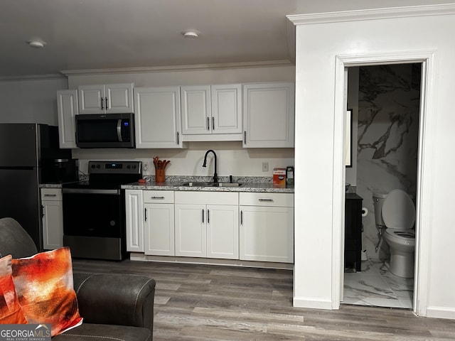 1550 Shady Oaks Ln, Greensboro, GA 30642 - kitchen featuring crown molding, appliances with stainless steel finishes, light stone counters, a sink, and light wood-type flooring