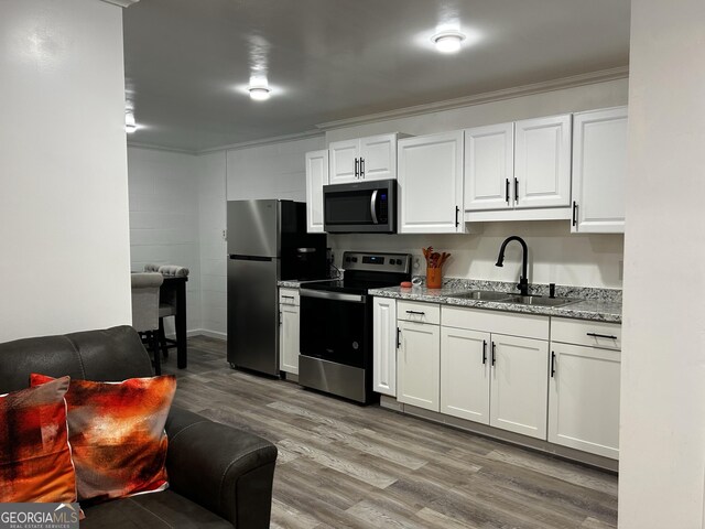 1550 Shady Oaks Ln, Greensboro, GA 30642 - kitchen with appliances with stainless steel finishes, a sink, white cabinets, light wood-style floors, and ornamental molding