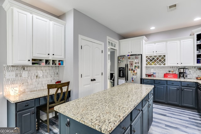 kitchen with white cabinetry, blue cabinetry, visible vents, and stainless steel fridge