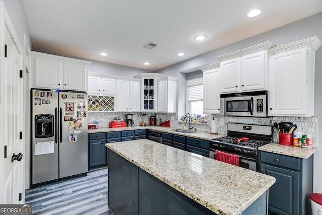 kitchen featuring blue cabinetry, white cabinets, stainless steel appliances, and a sink