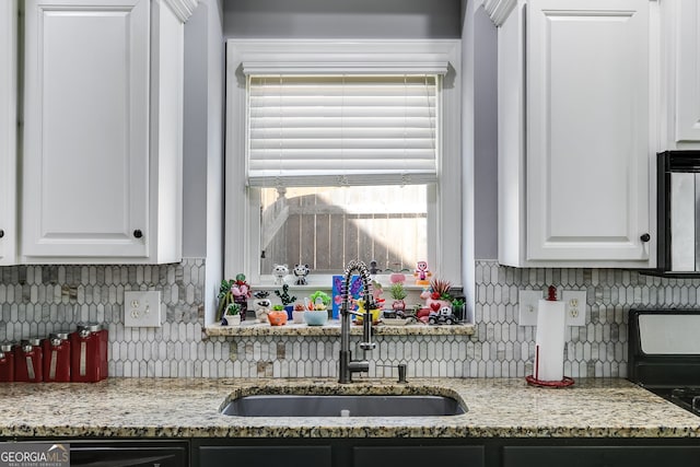 kitchen with white cabinets, light stone counters, tasteful backsplash, and a sink