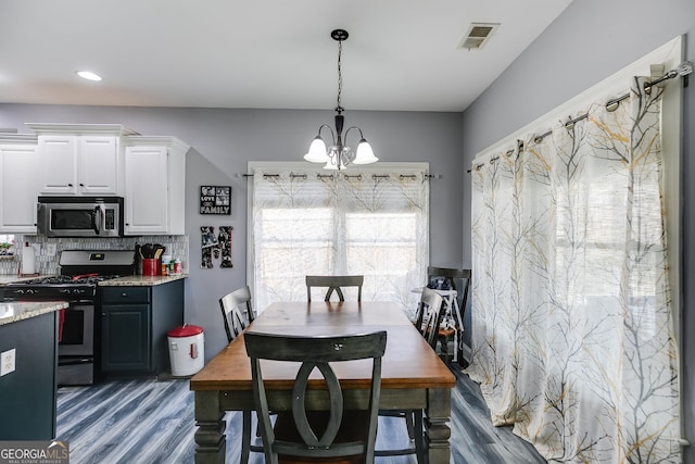 dining room featuring visible vents, wood finished floors, and a chandelier