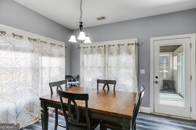 dining space with wood finished floors, a notable chandelier, a healthy amount of sunlight, and visible vents