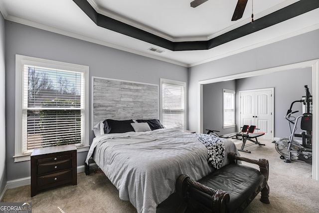 bedroom with a tray ceiling, visible vents, carpet floors, and ornamental molding