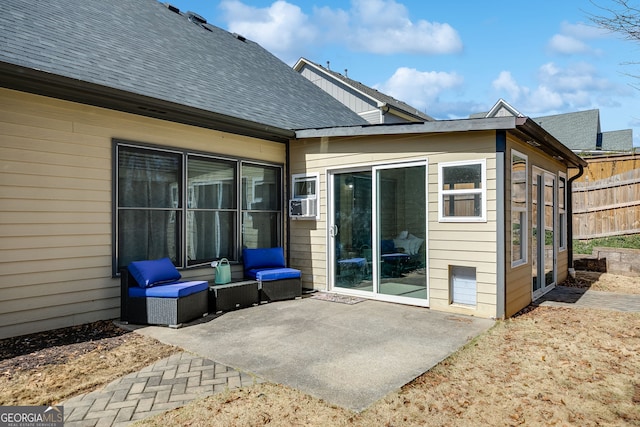 back of property featuring fence, a shingled roof, and a patio area