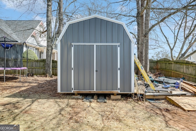 view of shed with a fenced backyard and a trampoline