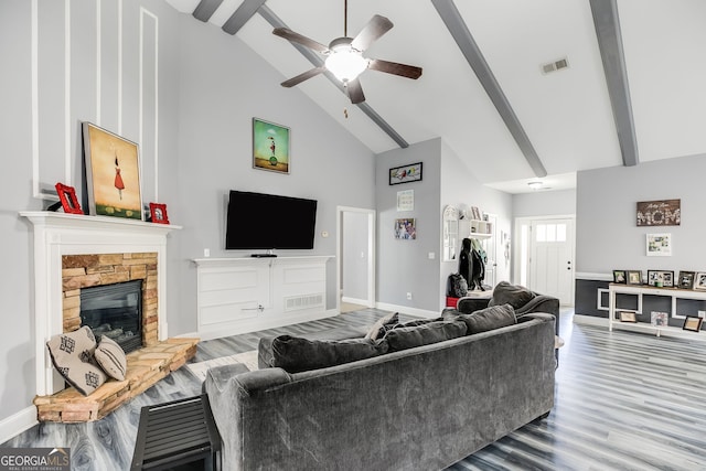 living area with visible vents, high vaulted ceiling, wood finished floors, a fireplace, and baseboards