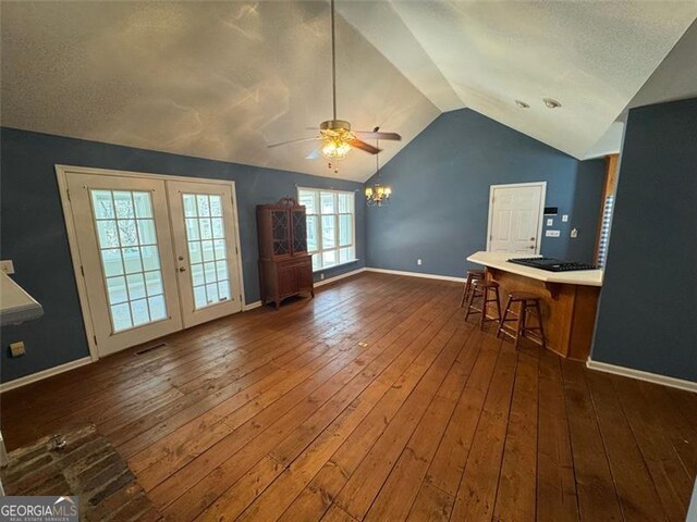 unfurnished living room featuring french doors, lofted ceiling, baseboards, and hardwood / wood-style floors