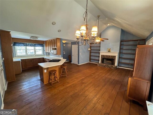 kitchen featuring a brick fireplace, dark wood finished floors, open floor plan, vaulted ceiling, and a peninsula