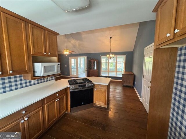 kitchen with white microwave, stainless steel gas range oven, a peninsula, and brown cabinets