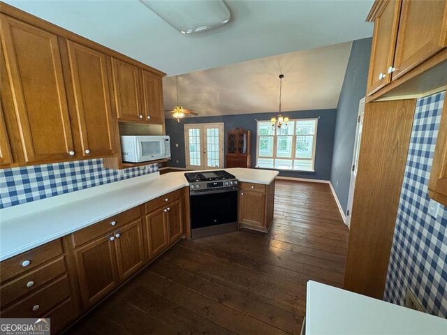 kitchen with white microwave, stainless steel gas stove, light countertops, a peninsula, and dark wood-style floors