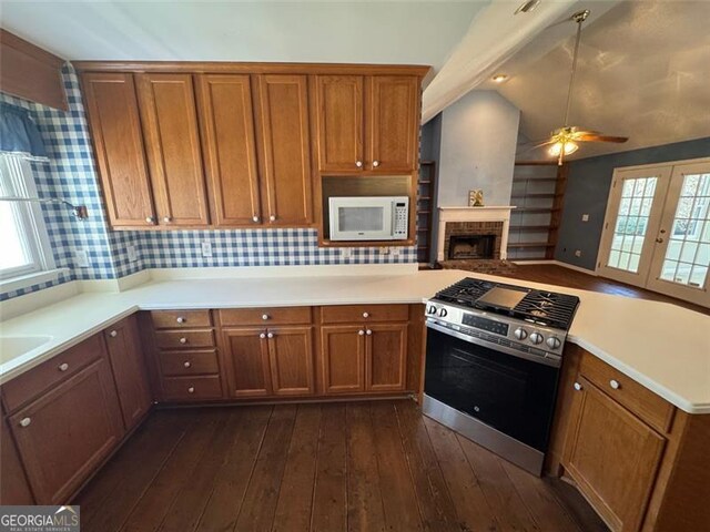 kitchen with brown cabinetry, white microwave, stainless steel gas stove, and vaulted ceiling