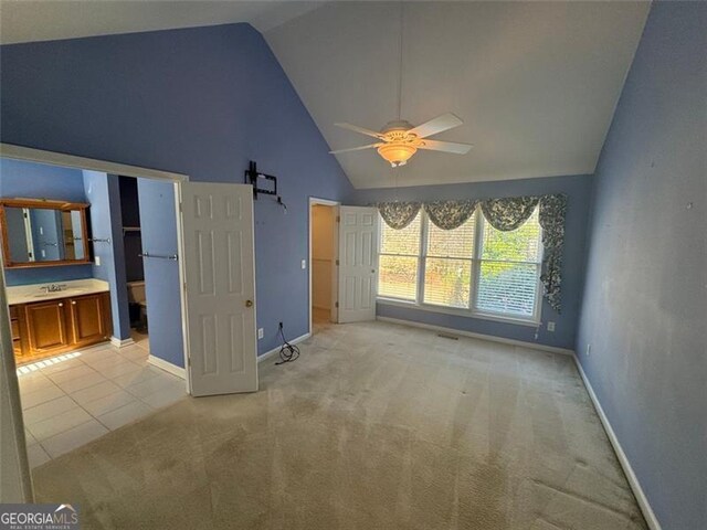 unfurnished bedroom with light tile patterned flooring, light colored carpet, baseboards, and high vaulted ceiling