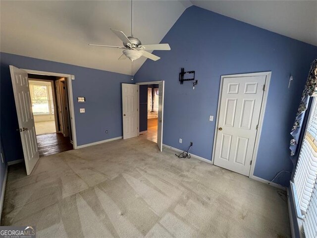 unfurnished bedroom with light colored carpet, high vaulted ceiling, and baseboards