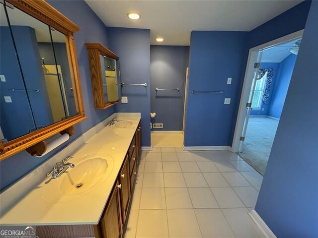 full bathroom with a sink, baseboards, double vanity, and tile patterned flooring