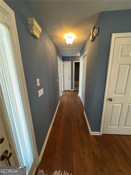 hallway with baseboards, attic access, and dark wood-style flooring