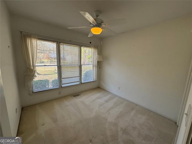 empty room featuring visible vents, light carpet, and a ceiling fan