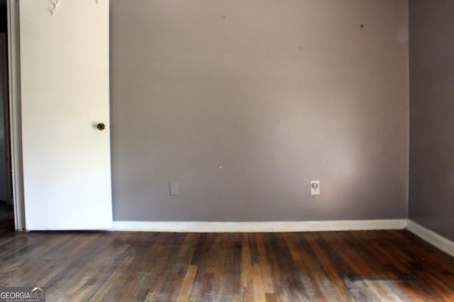 spare room with baseboards and wood finished floors