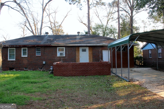 rear view of house with driveway, brick siding, a detached carport, and a lawn