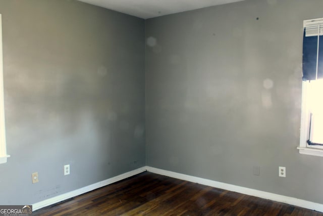 unfurnished room featuring baseboards and dark wood finished floors