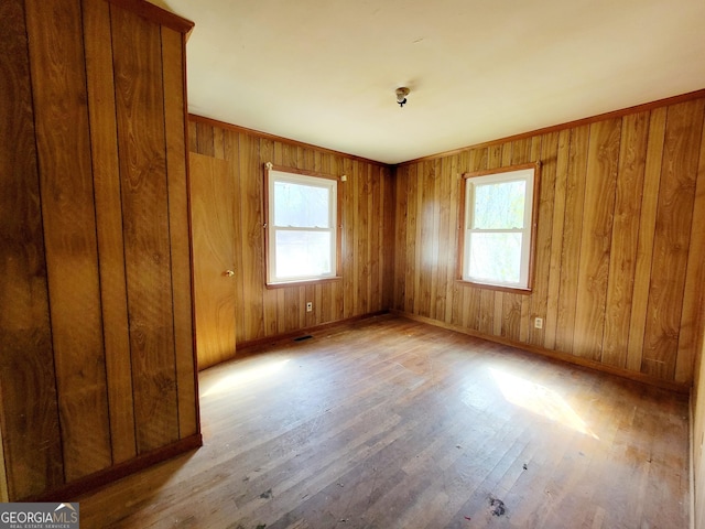 unfurnished room with a wealth of natural light, visible vents, baseboards, and hardwood / wood-style floors