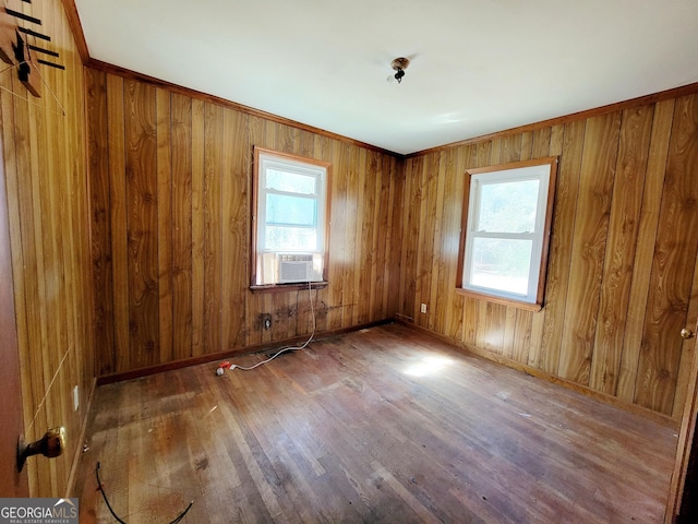 empty room featuring hardwood / wood-style floors, wooden walls, cooling unit, and baseboards