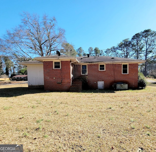 back of house featuring brick siding and a lawn