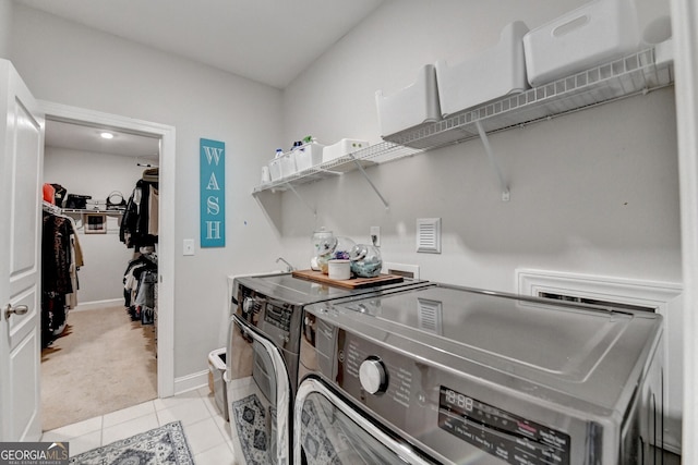 laundry area with washing machine and dryer, laundry area, baseboards, light tile patterned floors, and light colored carpet