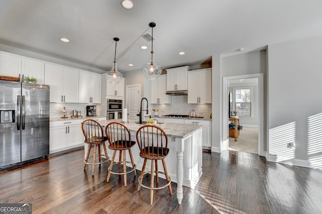 kitchen with visible vents, a center island with sink, a sink, white cabinetry, and stainless steel appliances