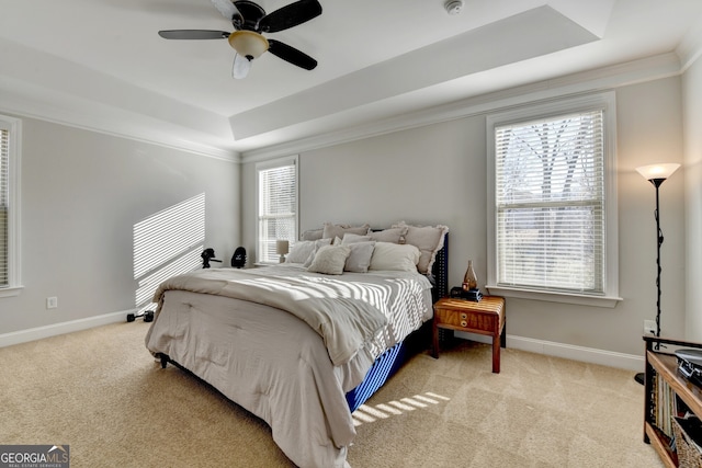 carpeted bedroom featuring multiple windows, a raised ceiling, and baseboards